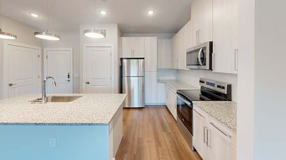 A kitchen with white cabinets and a blue island.