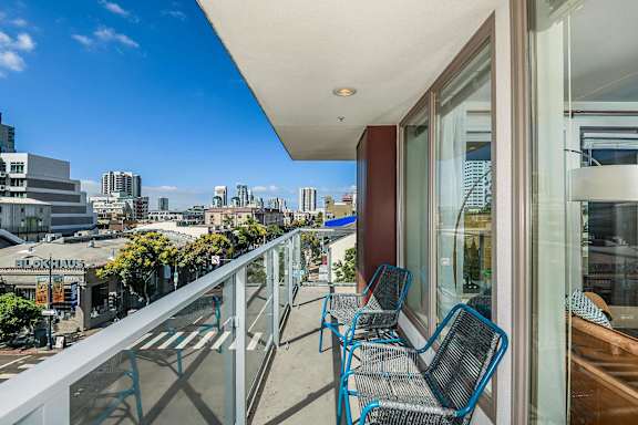 A balcony with blue chairs and a view of a city skyline.
