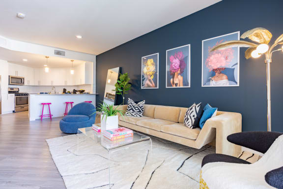 a living area with a couch coffee table and chairs and a kitchen in the background at Chandler Apartments in North Hollywood, North Hollywood