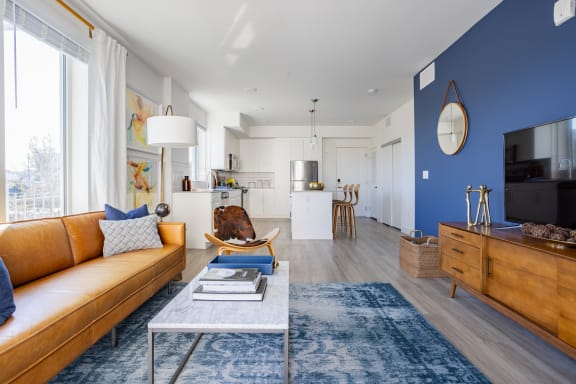 a living room with a blue accent wall and a brown leather couch at Chandler Apartments in North Hollywood, North Hollywood, CA, California