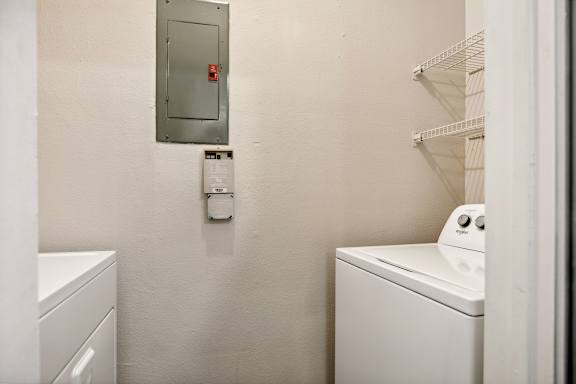 A white dryer is next to a white washing machine in a small laundry room.
