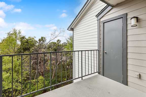 A balcony with a metal railing and a grey door.