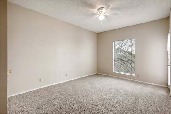 A room with a carpeted floor and a ceiling fan.