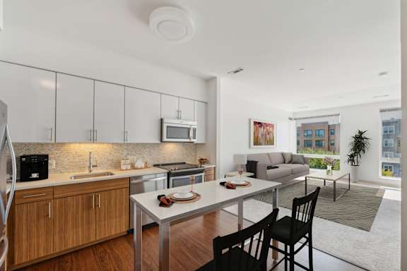 A modern kitchen with wooden cabinets and a dining table with chairs. at The Merc, Waltham, 02453