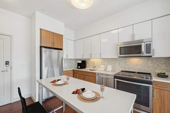 A modern kitchen with a dining table set for two. at The Merc, Waltham, MA, 02453