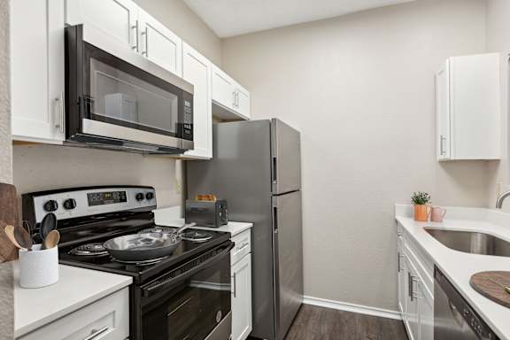 A kitchen with black and white appliances and white cabinets.