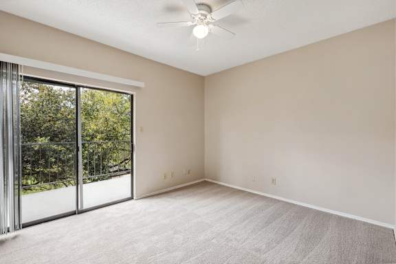 A room with a ceiling fan and sliding glass doors.