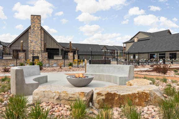 a patio with chairs and a fire pit in front of a building