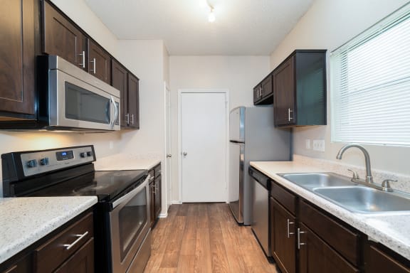 A kitchen with dark wood cabinets and stainless steel appliances.