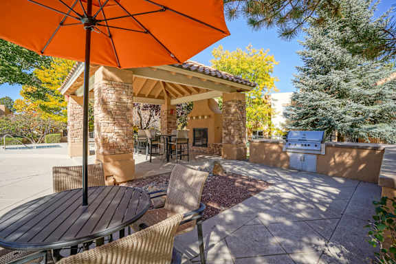 A patio with a table and chairs under an orange umbrella.