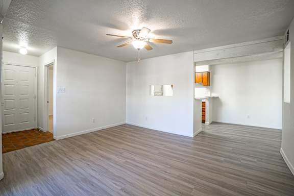 A room with a ceiling fan and wooden flooring.