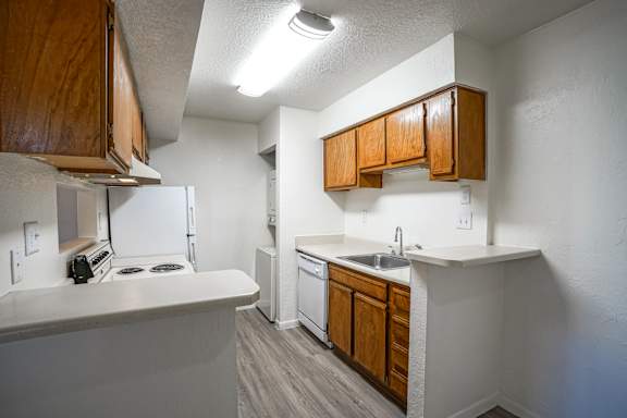 A kitchen with white countertops and wooden cabinets.