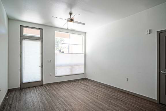 A room with a ceiling fan and a door leading to a balcony.