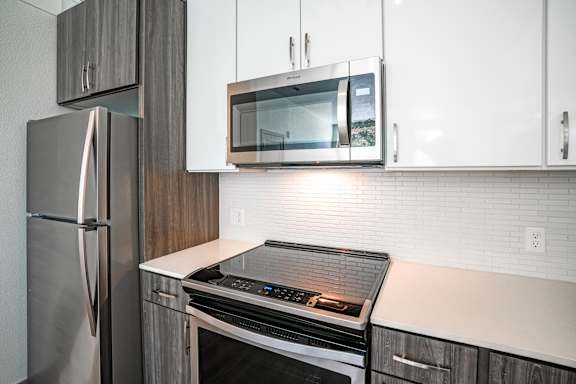 A modern kitchen with a stainless steel refrigerator, microwave, and oven.