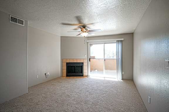 A living room with a fireplace and a ceiling fan.