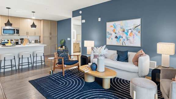 A modern living room with a kitchen area in the background.