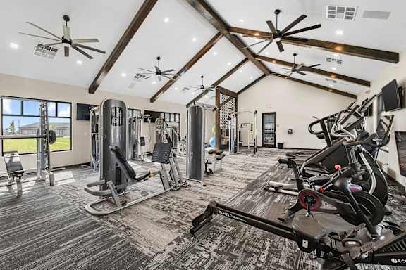 A spacious gym with a variety of equipment and a large window.
