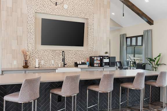 A modern kitchen with a bar area and a television mounted on the wall.