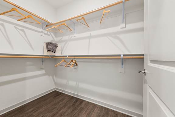 A white closet with wooden hangers and a towel hanging on the shelf.