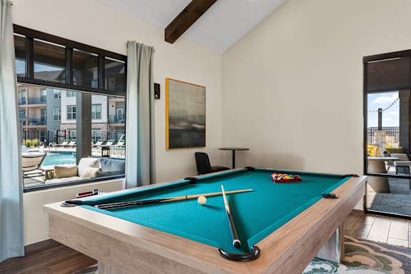 A pool table in a room with a view of the outside.