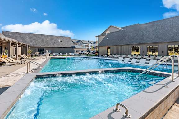 A large outdoor swimming pool with a wooden deck and lounge chairs.
