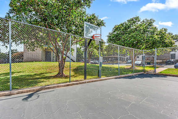 A basketball hoop is attached to a chain link fence.