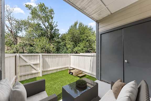 A patio with a couch, table, and a potted plant.