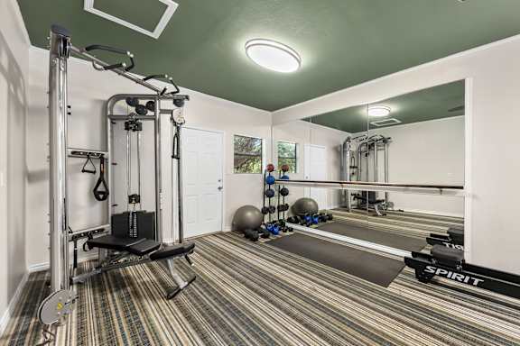 A gym with a weight bench and a mirror.