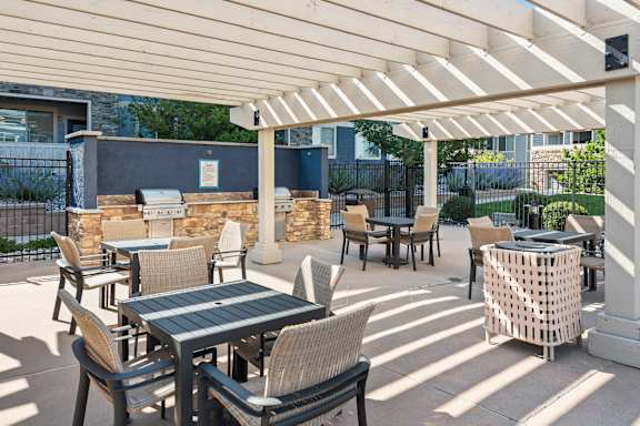 A patio with tables and chairs under a white canopy.