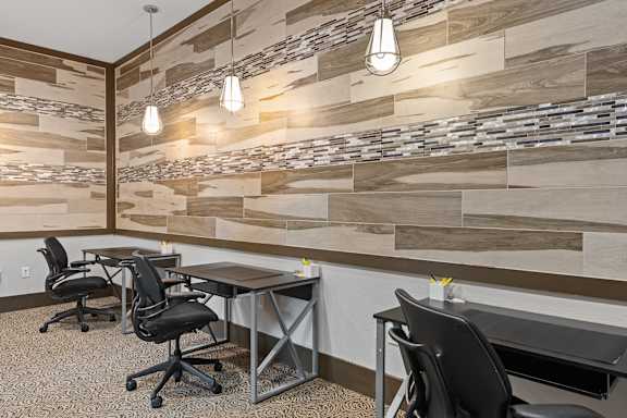 A modern office with wood paneling on the wall and black chairs.