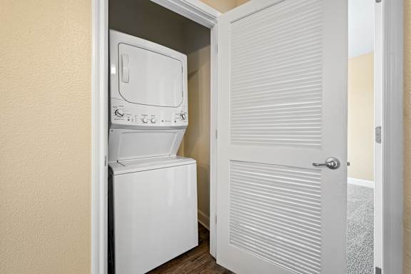 A white dishwasher is installed in a narrow space between two walls.
