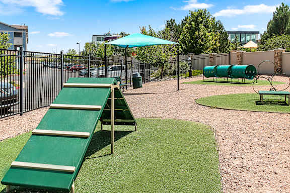 A playground with a green slide and a green umbrella.