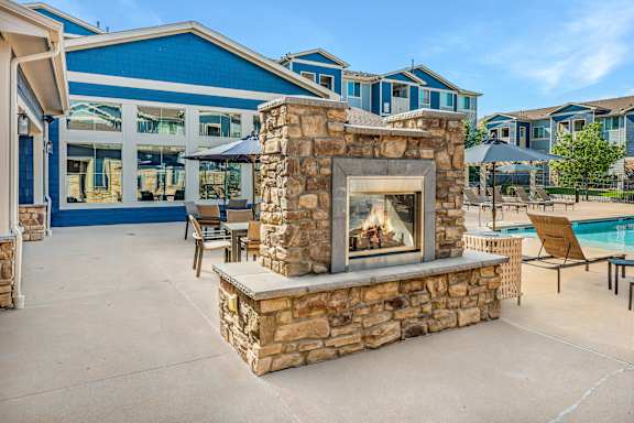 A stone fireplace is in the middle of a patio.