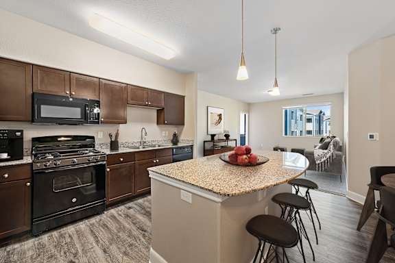 A kitchen with a granite countertop and bar stools.