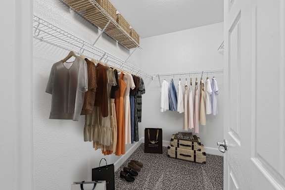A hallway with clothes hanging on a rack and a bag on the floor.