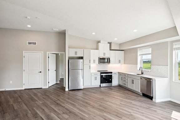 A kitchen with white appliances and wooden floors.