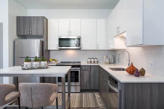 A modern kitchen with a white table and grey cabinets.