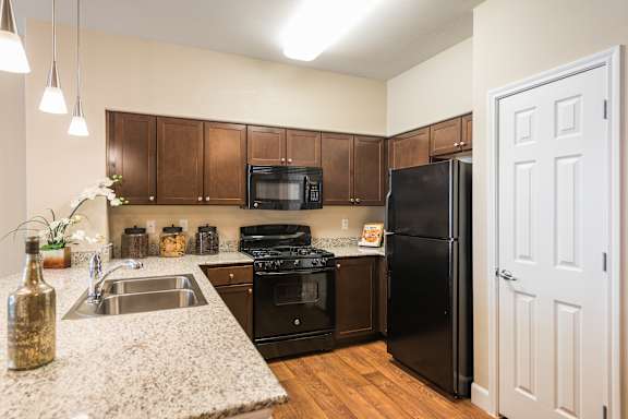 A kitchen with black appliances and wooden cabinets.