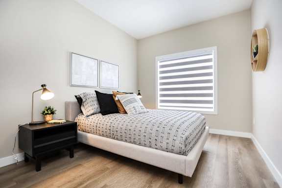 A bedroom with a bed, nightstand, and a lamp.