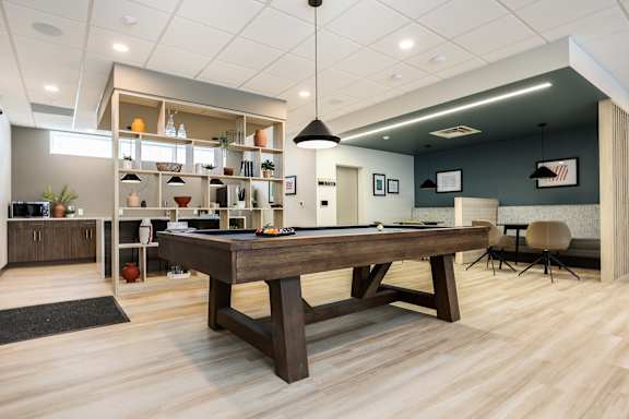 A room with a pool table and a bar area.