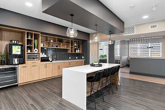 a large kitchen with a white island and black chairs