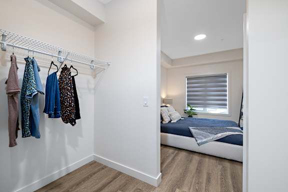 a bedroom with a bed and a closet with clothes hanging on the wall