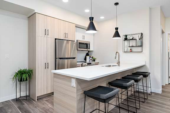 A kitchen with a white countertop and black bar stools.