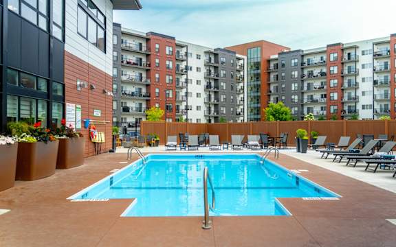 A large swimming pool surrounded by lounge chairs and apartment buildings.at Latitude 49 Townhomes, Winnipeg, R3X 0M1