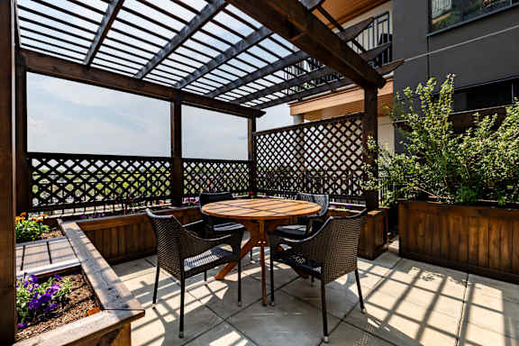 A patio with a table and chairs under a wooden roof.at Raymond Block, Edmonton, AB