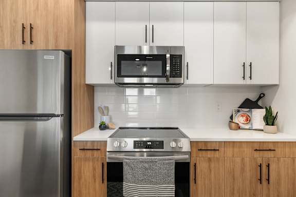 A modern kitchen with a stainless steel refrigerator, microwave, and oven.
