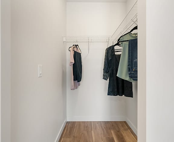 Clothes hanging on a clothes rack in a room. at Podium Apartments, Calgary, AB