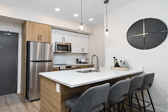 A modern kitchen with a stainless steel refrigerator, a microwave, and a white countertop.