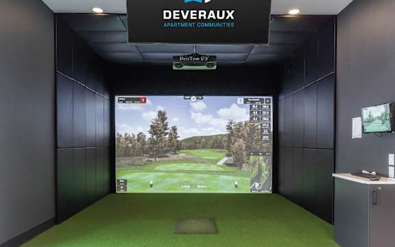 A golf simulator room with a screen showing a golf course.