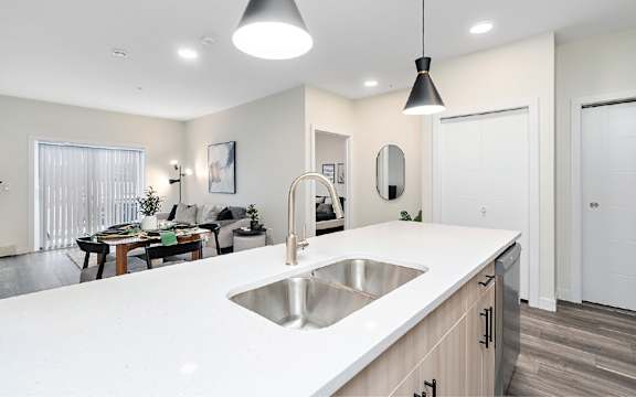 A modern kitchen with a white countertop and wooden cabinets.